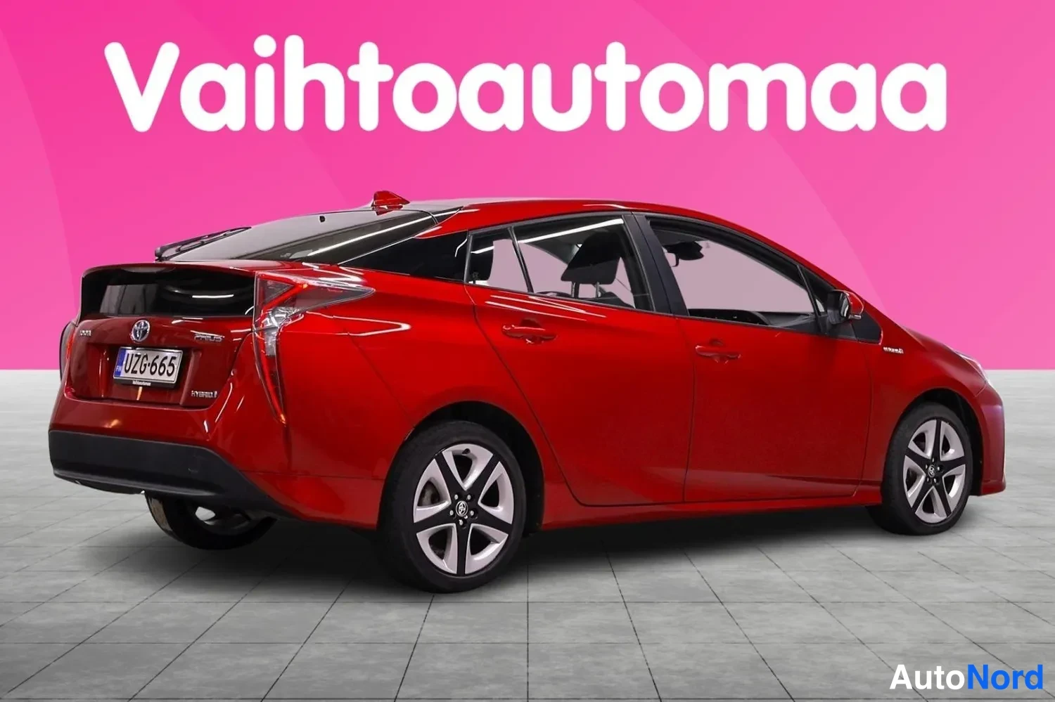 Takaviisto: Punaisen Toyota Priuksen takakulmanäkyvyys, rekisterikilpi, takaa ja vasenta kylkeä näkyy.