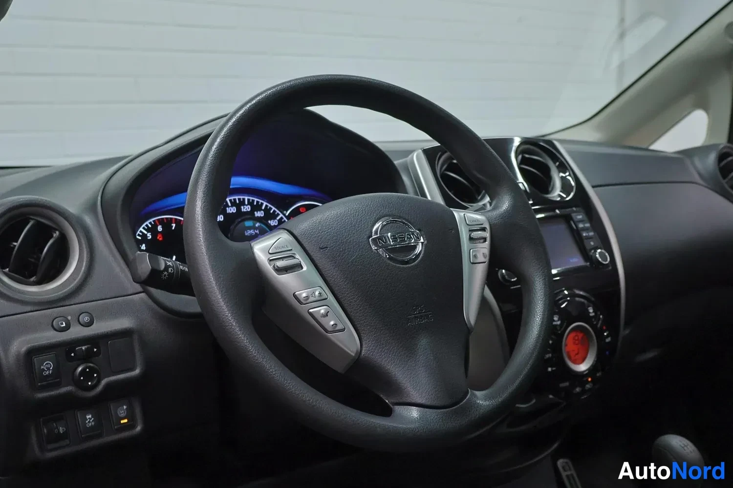 Muu: Nissan Note 2014: ohjauspyörä Nissan-logolla, mittaristo ja keskikonsolin näyttö ja radiopaneeli.