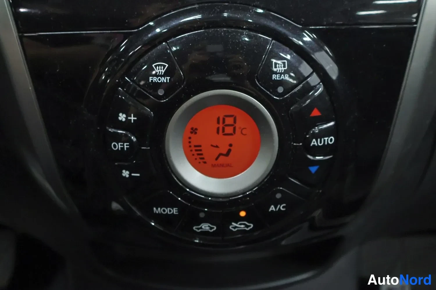 Yksityiskohta: Ympyrämuotoinen automaattisen ilmastoinnin ohjauspaneeli, jonka näytössä 18 °C ja AUTO-, A/C-, MODE-, FRONT- ja REAR-painikkeet.