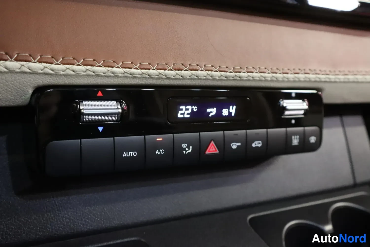 Yksityiskohta: Ilmastointilaitteen ohjauspaneeli, jossa näyttö näyttää 22 astetta ja painikkeet AUTO ja A/C.