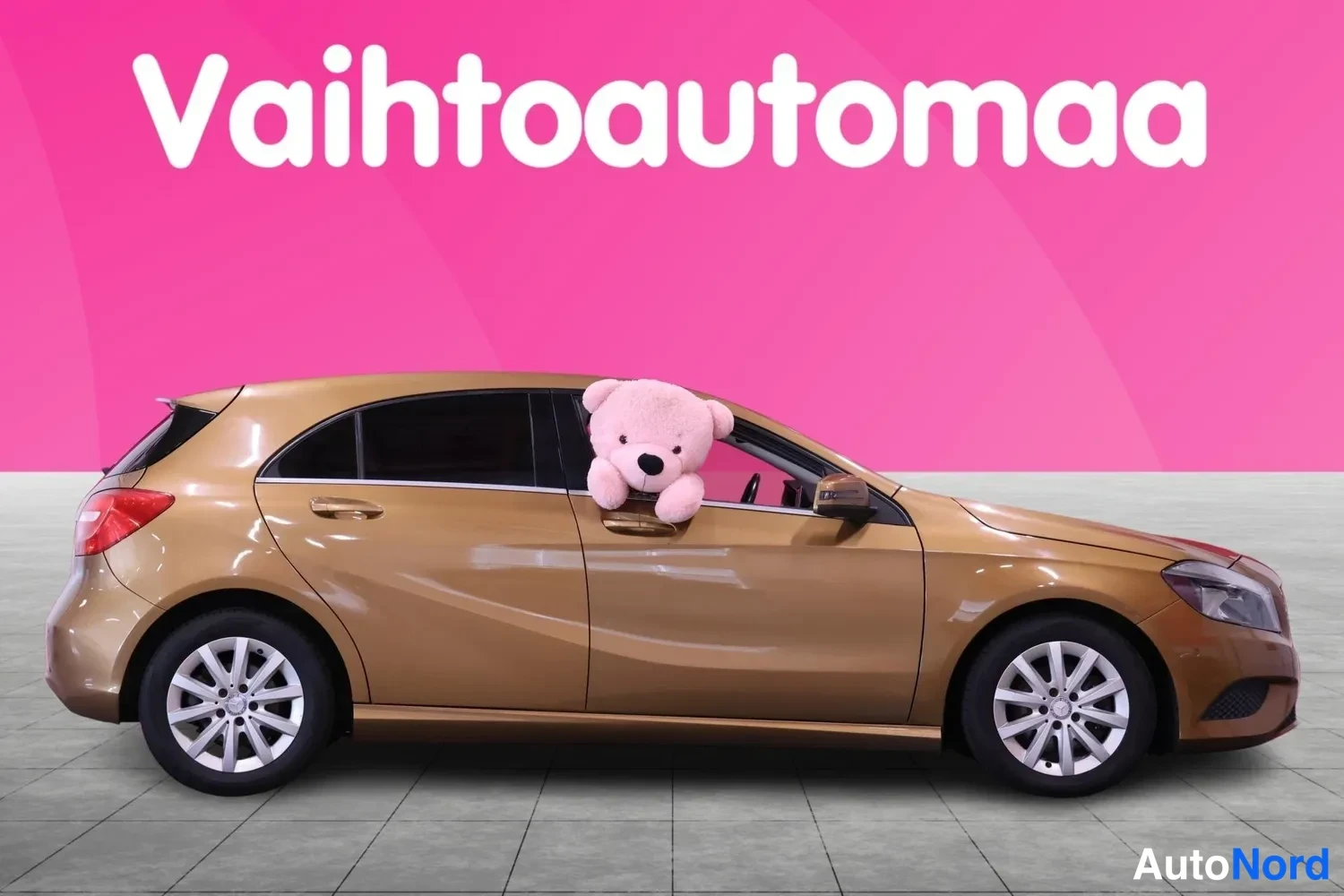 Sivulta: Mercedes-Benz A 180 sivukuva oikealta, kuparinruskea hatchback, pehmolelu ikkunassa.