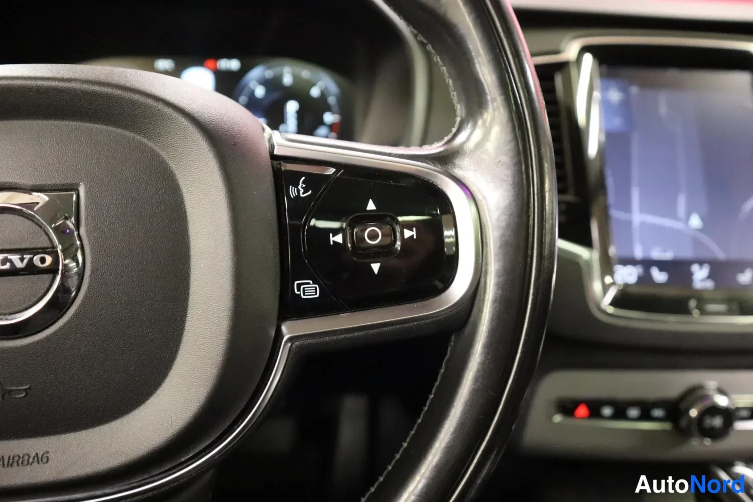 Muu: Volvo-ohjauspyörän oikean puolen painikkeet, Sensus-näyttö ja mittaristo taustalla.