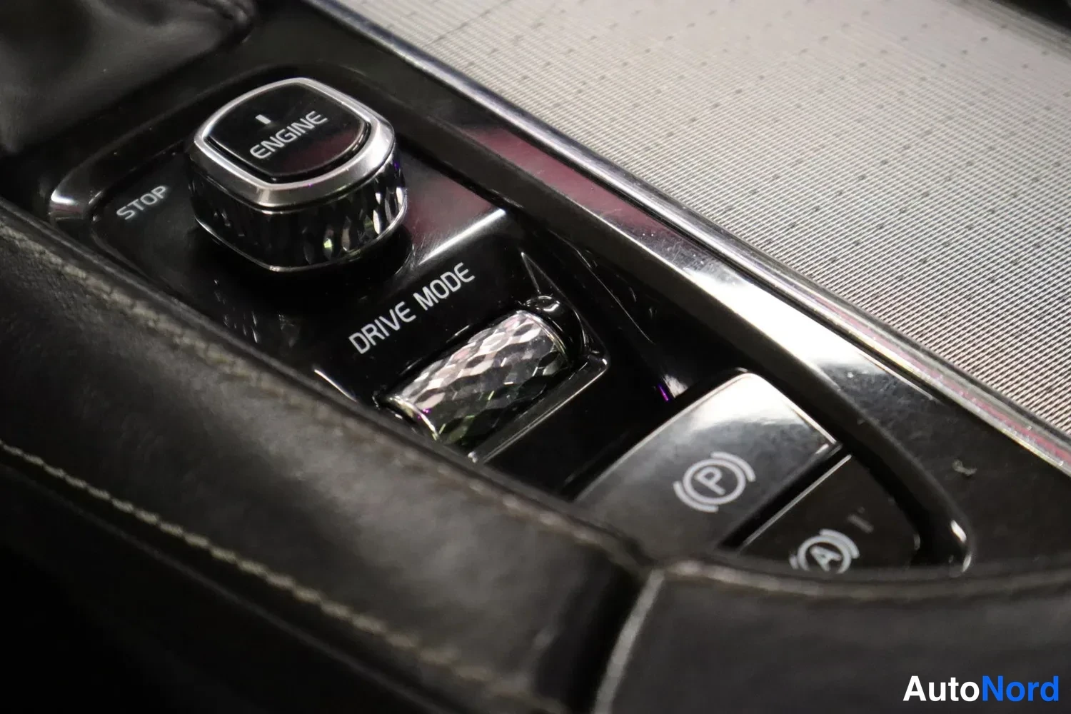 Muu: Sisätilakuva keskikonsolin START/STOP ENGINE -painikkeesta, DRIVE MODE -rullasta ja sähköisestä seisujarrunapista.