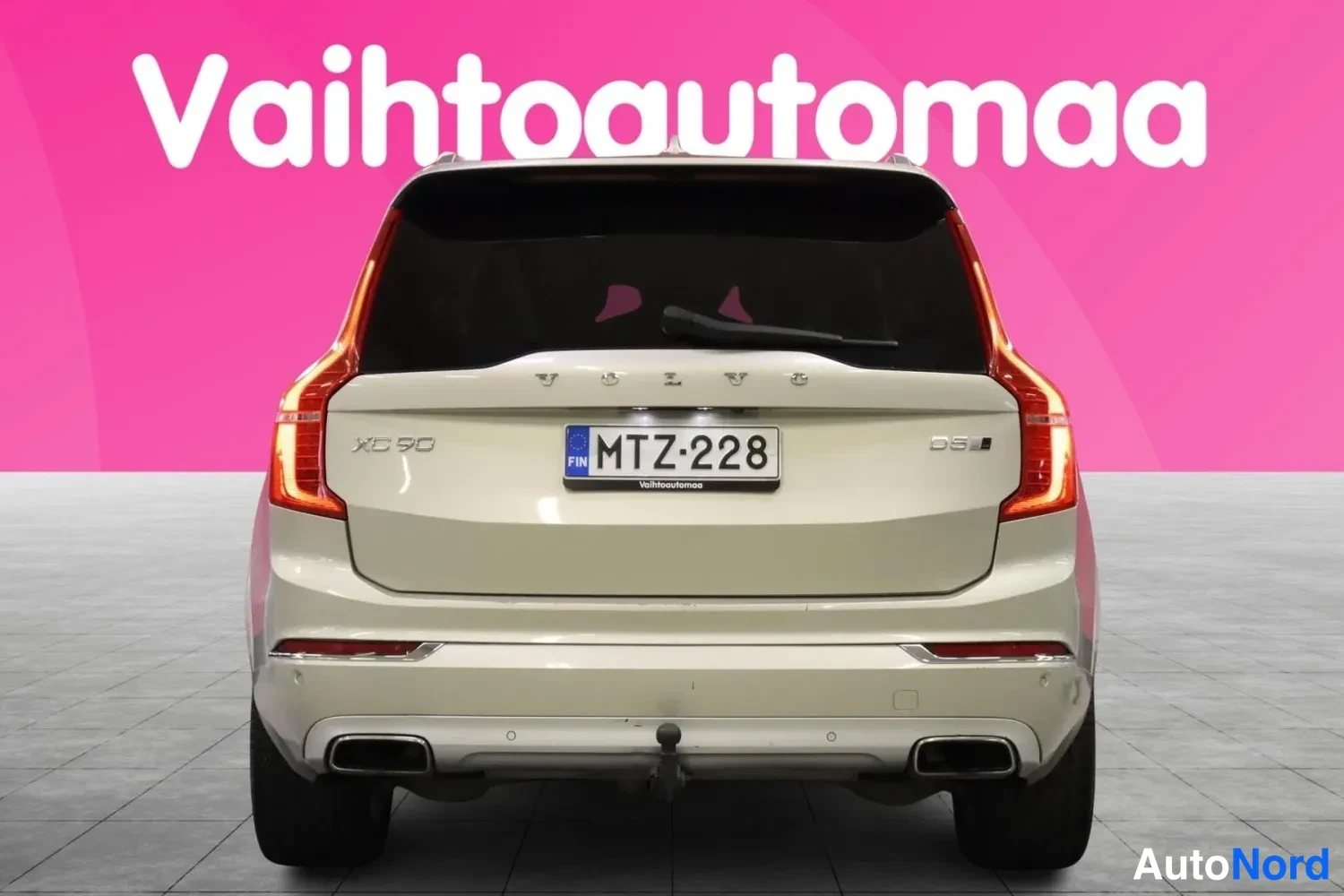 Takaa: Suora takanäkymä beigea automobiilistä, XC90- ja D5-merkinnät sekä -rekisterikilpi näkyvät.