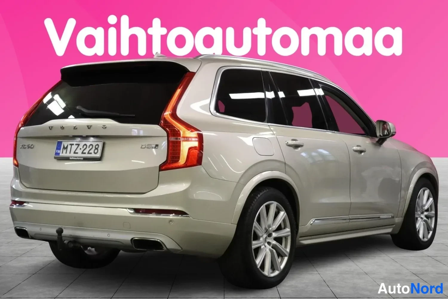 Takaviisto: Auton takaosa vasemmalta kolmen neljäsosan kuvakulmasta; beige koriväri, XC90-merkintä, -rekisterikilpi ja vetokoukku näkyvät.
