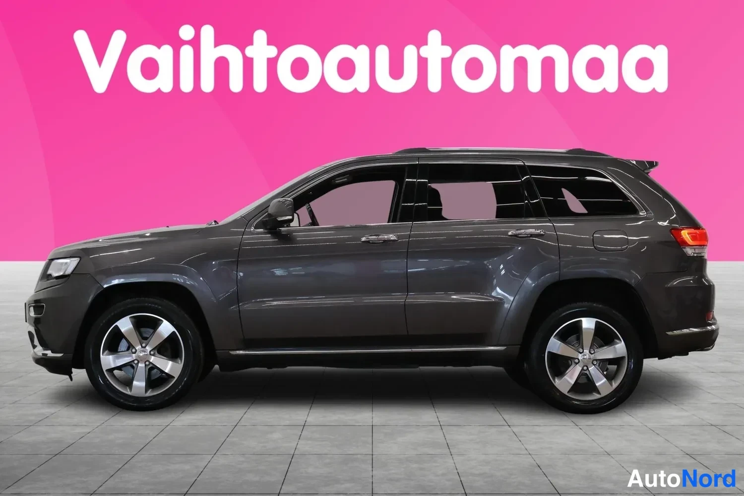 Sivulta: Tummanharmaa farmismaisen kombon mallinen SUV auton vasemman sivuprofiilin kuvassa studiokehystuksessa.