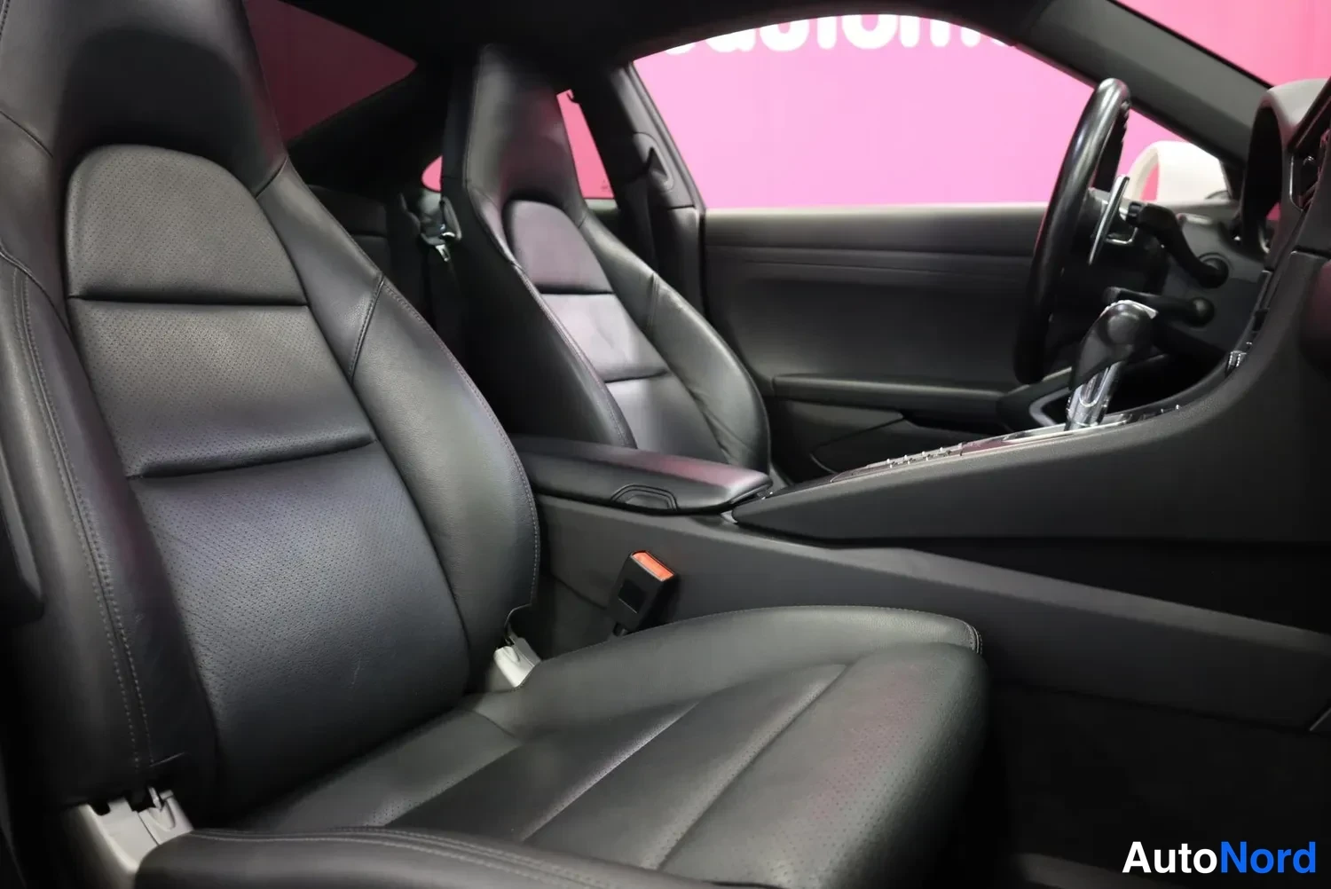 Muu: Porsche 911:n etuistuimet ja matkustamo mustilla nahkapenkeillä, ohjauspyörä ja keskikonsoli näkyvissä.