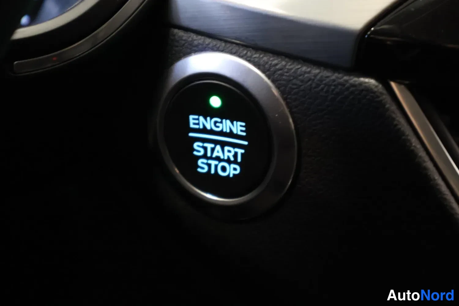Yksityiskohta: Avoimen nappi kytkin: ENGINE START STOP -teksti vihreällä valolla.