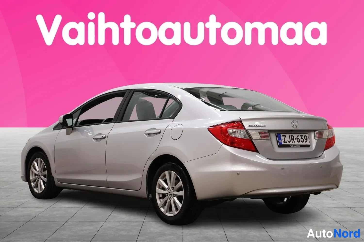 Takaviisto: Hopeanharmaa Honda Civic -sedan takaa kulmasta kuvattuna; takavalot, rekisterikilpi ja Honda-merkki näkyvät.