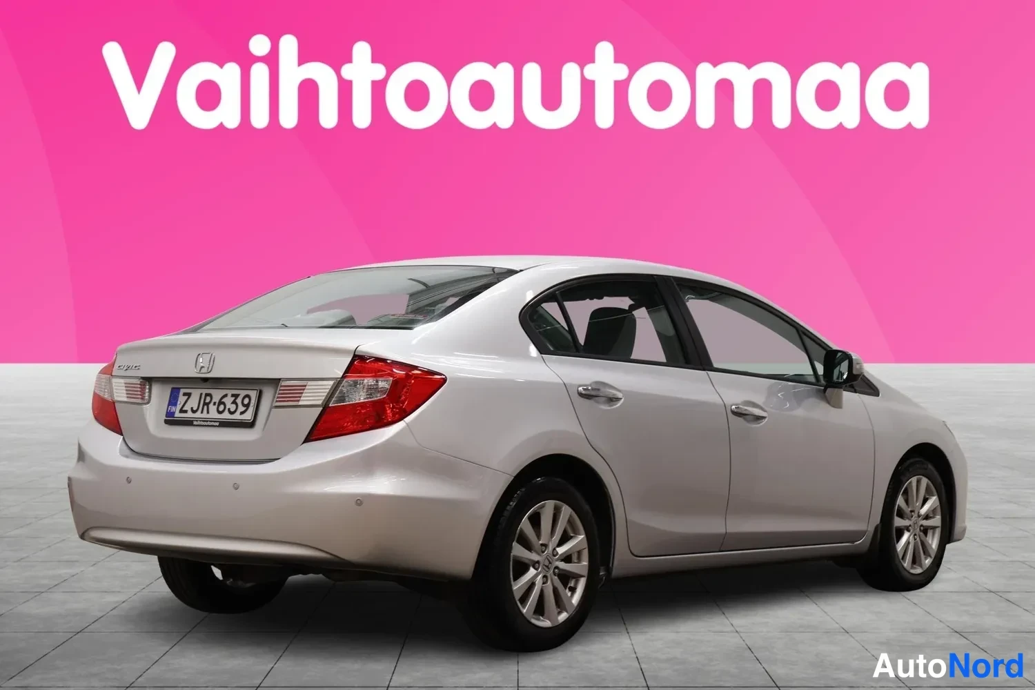 Takaviisto: Hopeanharmaa Honda Civic -sedan takaa sivulta kuvattuna; takaosa ja oikea sivu näkyvät, rekisterikilpi.