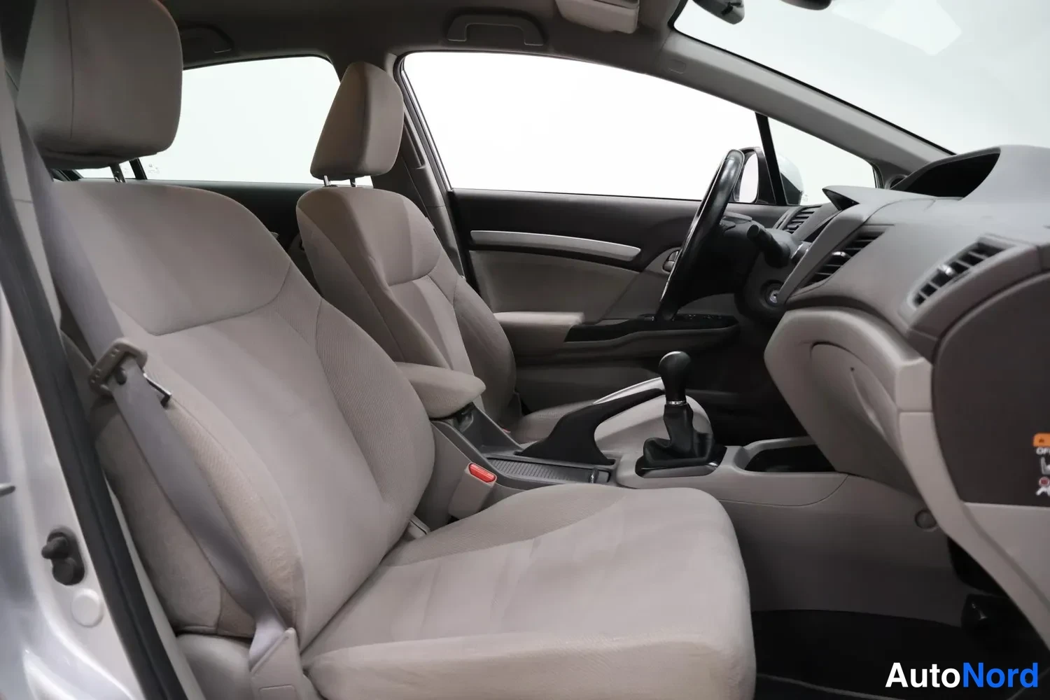 Edestä: Honda Civicin etupenkki ja koriin nähden musta etuosa kankaalla; käsijarrukeila ja manuaalivaihteiston vaihdekeila näkyvät matkustamossa.