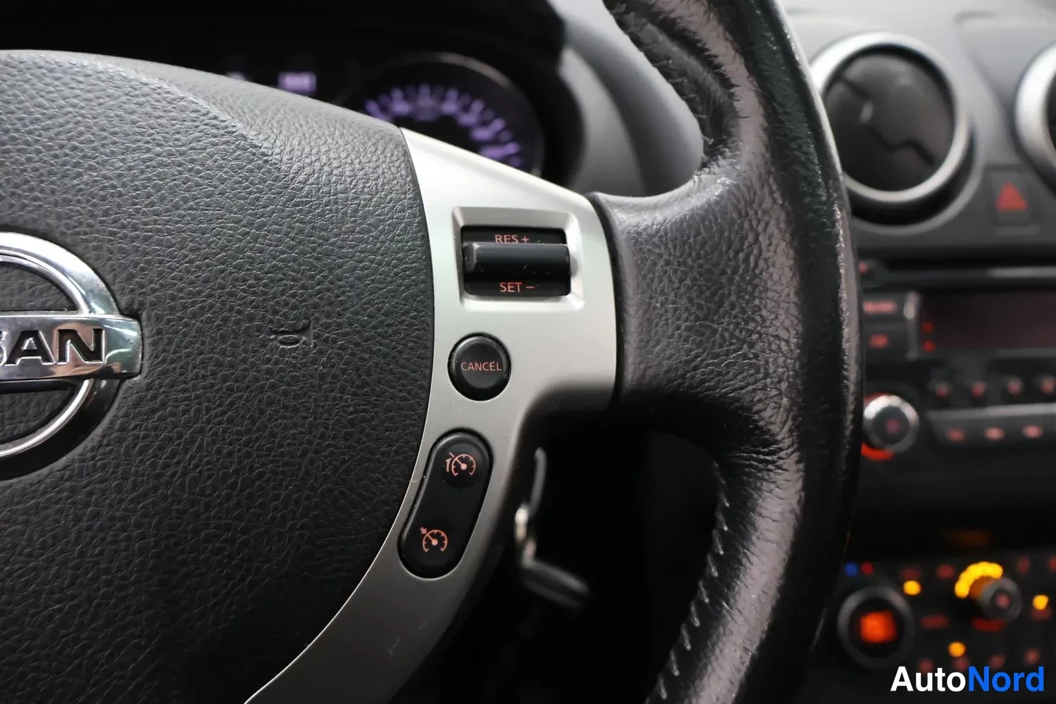 Muu: Ohjauspyörän puhelinpainikkeet ja vakkuripainikkeet: RES+, SET− ja CANCEL näkyvät Nissan-merkityn ohjauspyörän oikeassa kyljessä.