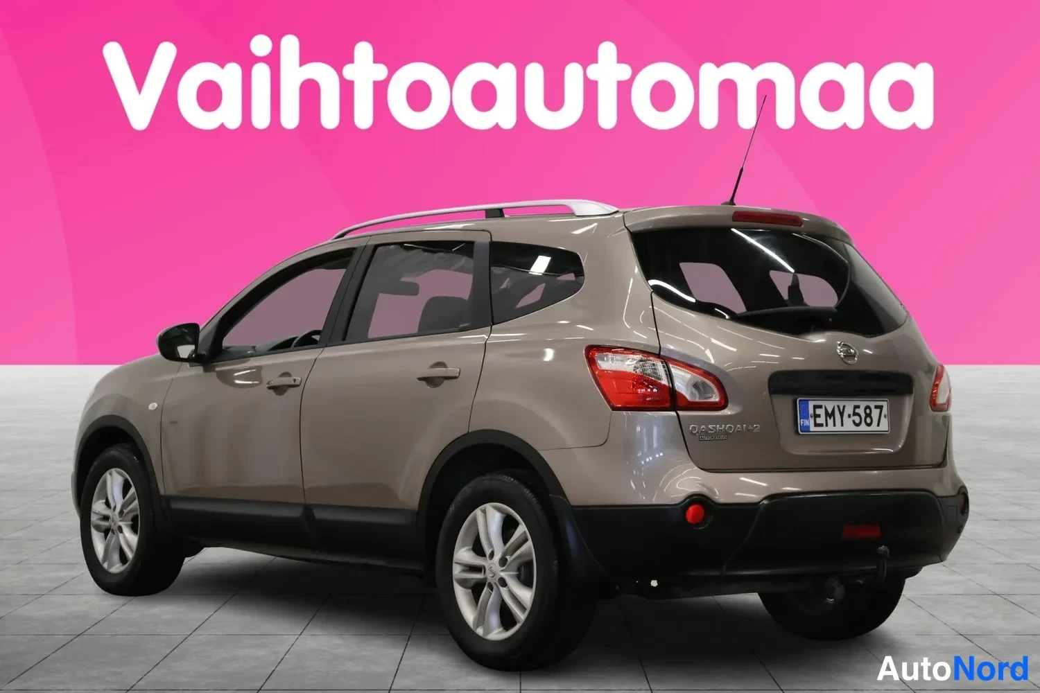 Takaviisto: Auton takakulma kolmivartalokuvassa: ruskeanbeige farmarimallinen Nissan, rekisterikilpi, kattokaiteet ja perävaunun kytkin näkyvät.