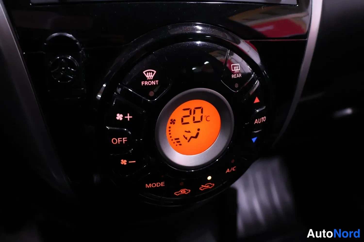 Yksityiskohta: Ilmastonhallintapaneelin lähikuva. Keskellä oleva digitaalinen näyttö osoittaa lämpötilan '20 C'. Nämä ovat painikkeet ja kiertonupit: OFF, MODE, A/C, AUTO, REA