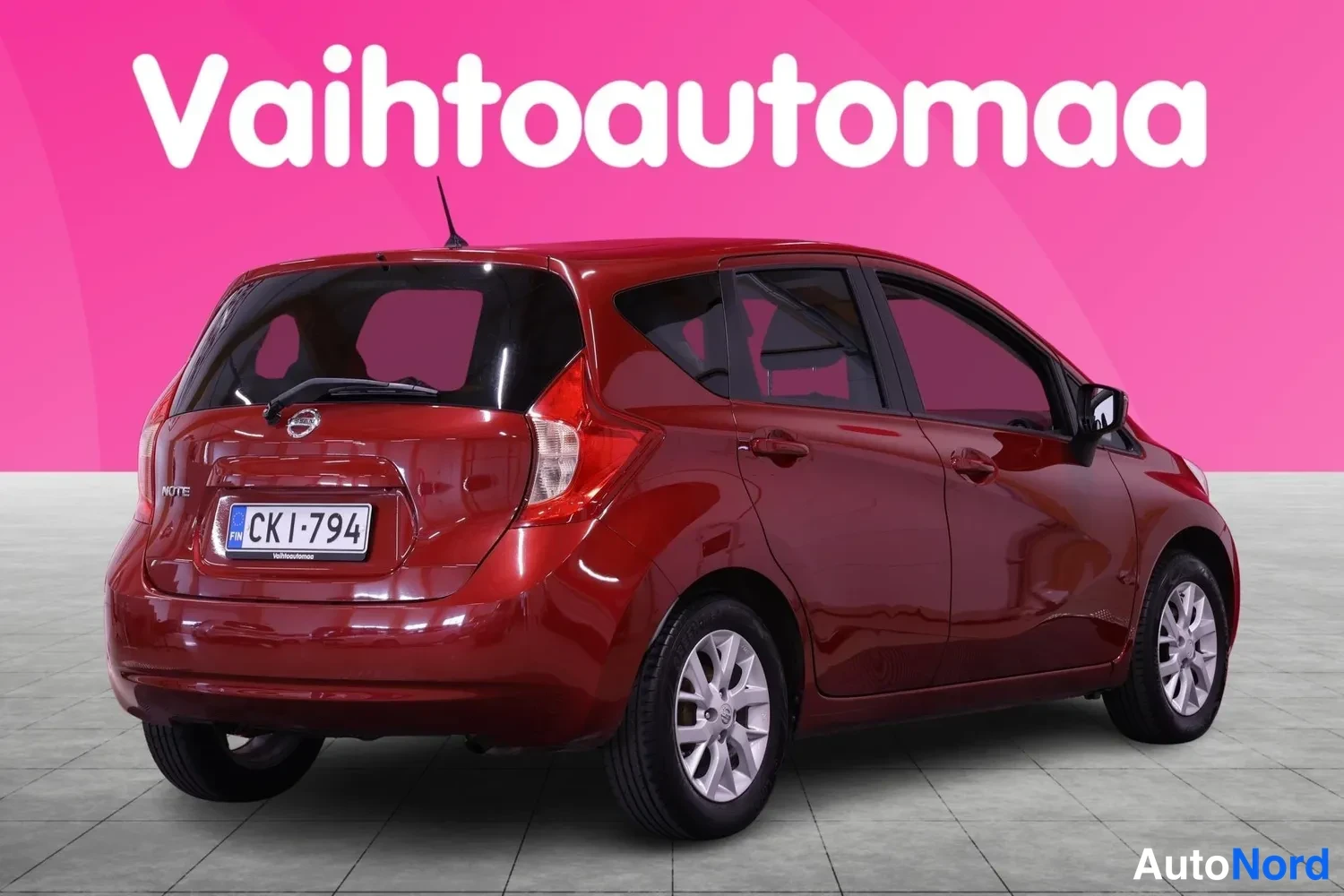 Takaviisto: Tummanpunaisen Nissan Note -henkilöauton takanäkymä kulmasta, rekisterikilpi näkyvissä.