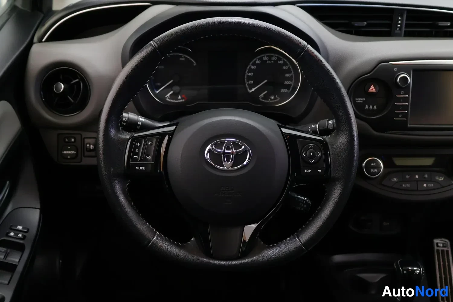 Muu: Ohjaamon kuvakaappaus: Toyota-ohjauspyörä, mittaristo ja keskikonsoli näkyvät.