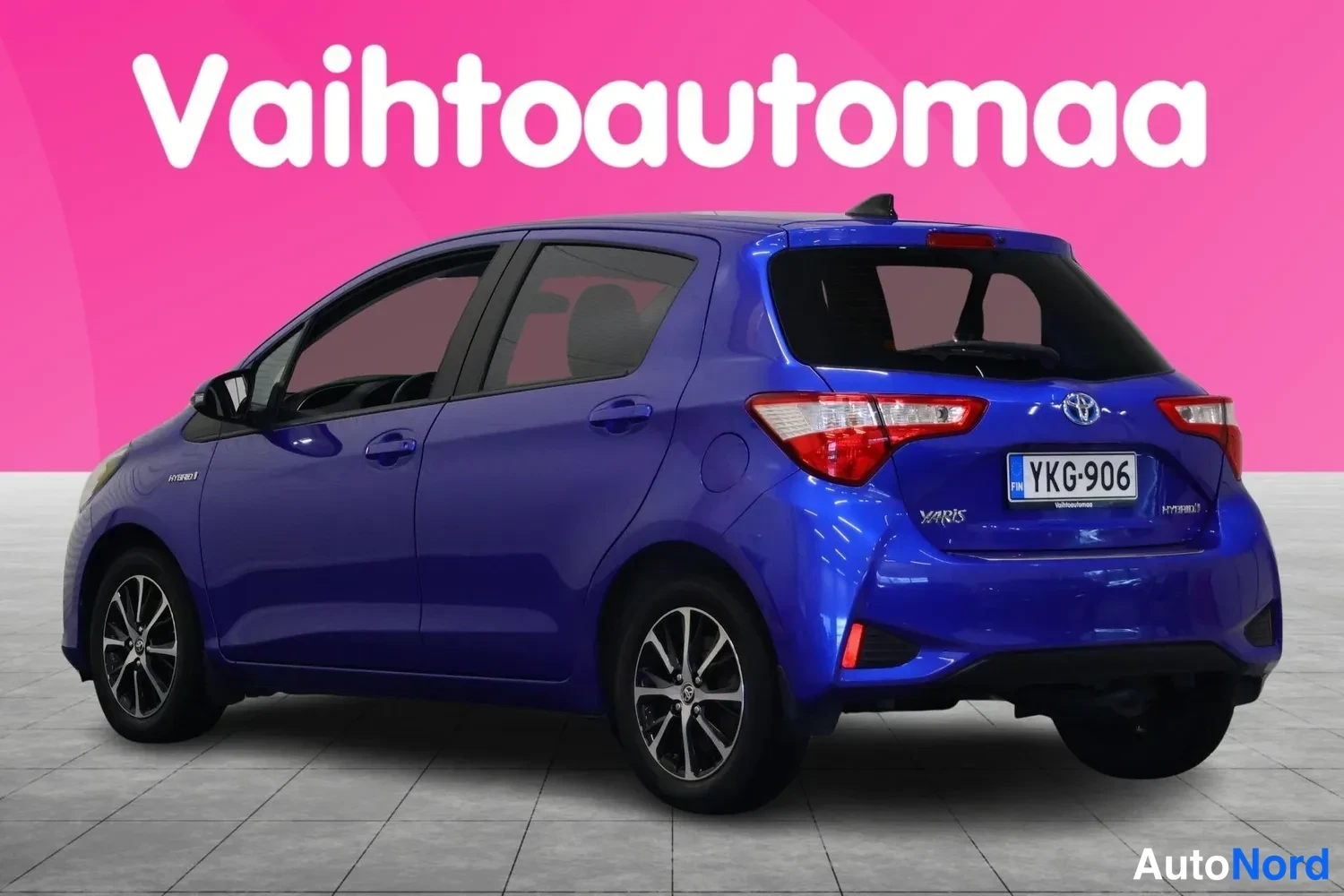 Takaviisto: Sininen Toyota Yaris -henkilöauto takaviistosta, perä ja vasen kylki näkyvissä, rekisterikilpi.