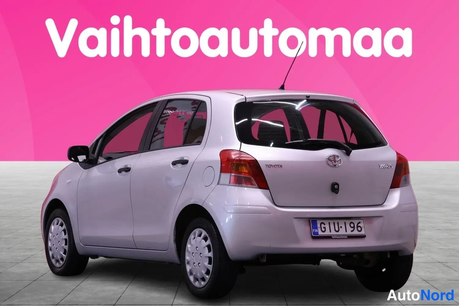 Takaviisto: Hopeanvärinen Toyota Yaris viistosti takaa, takavalot ja rekisterikilpi näkyvät.