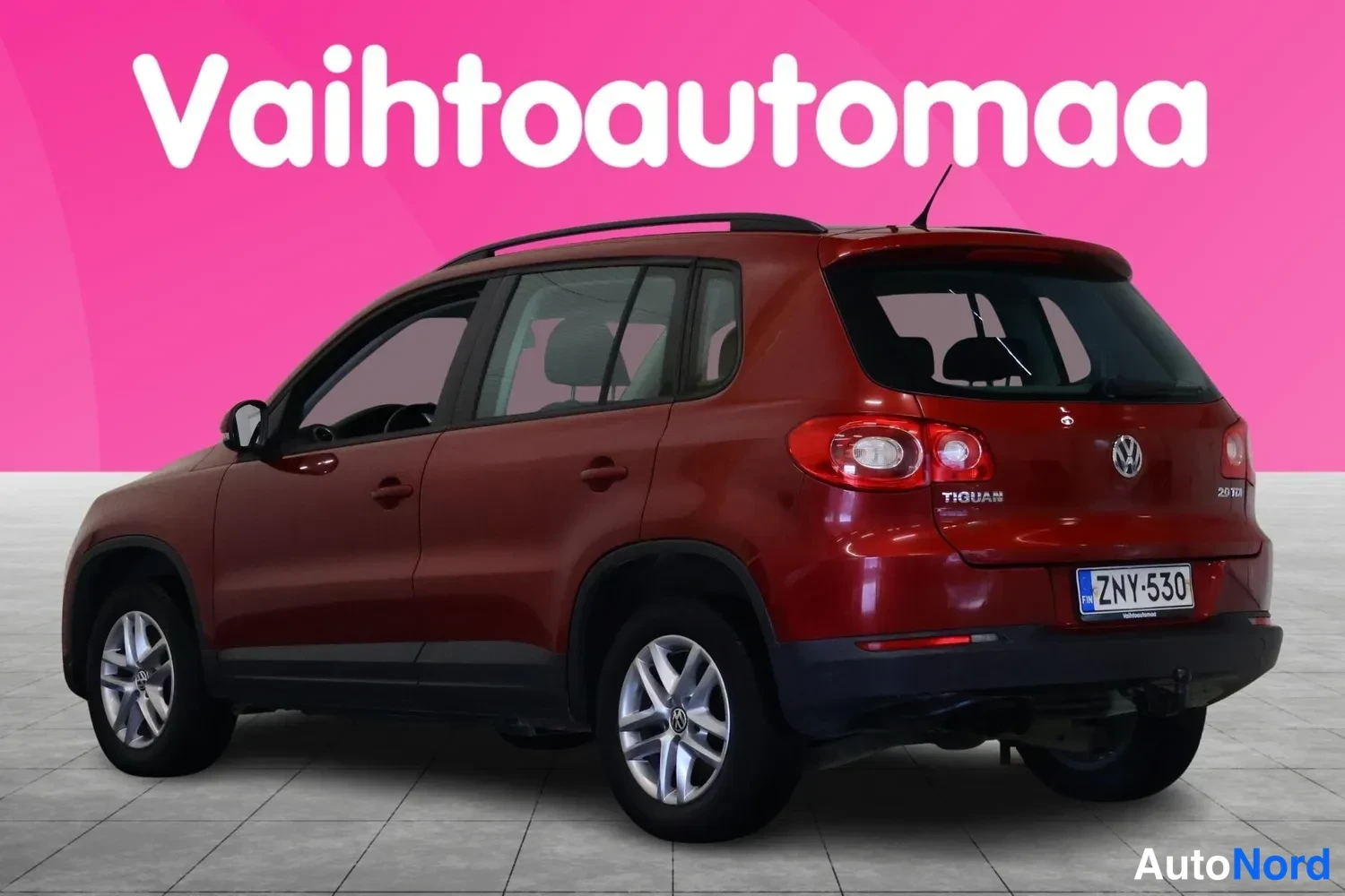 Takaviisto: Punaisenruskea Volkswagen Tiguan takaviistöstä, perä ja vasen kylki näkyvissä, kattokaiteet ja rekisteritunnus.