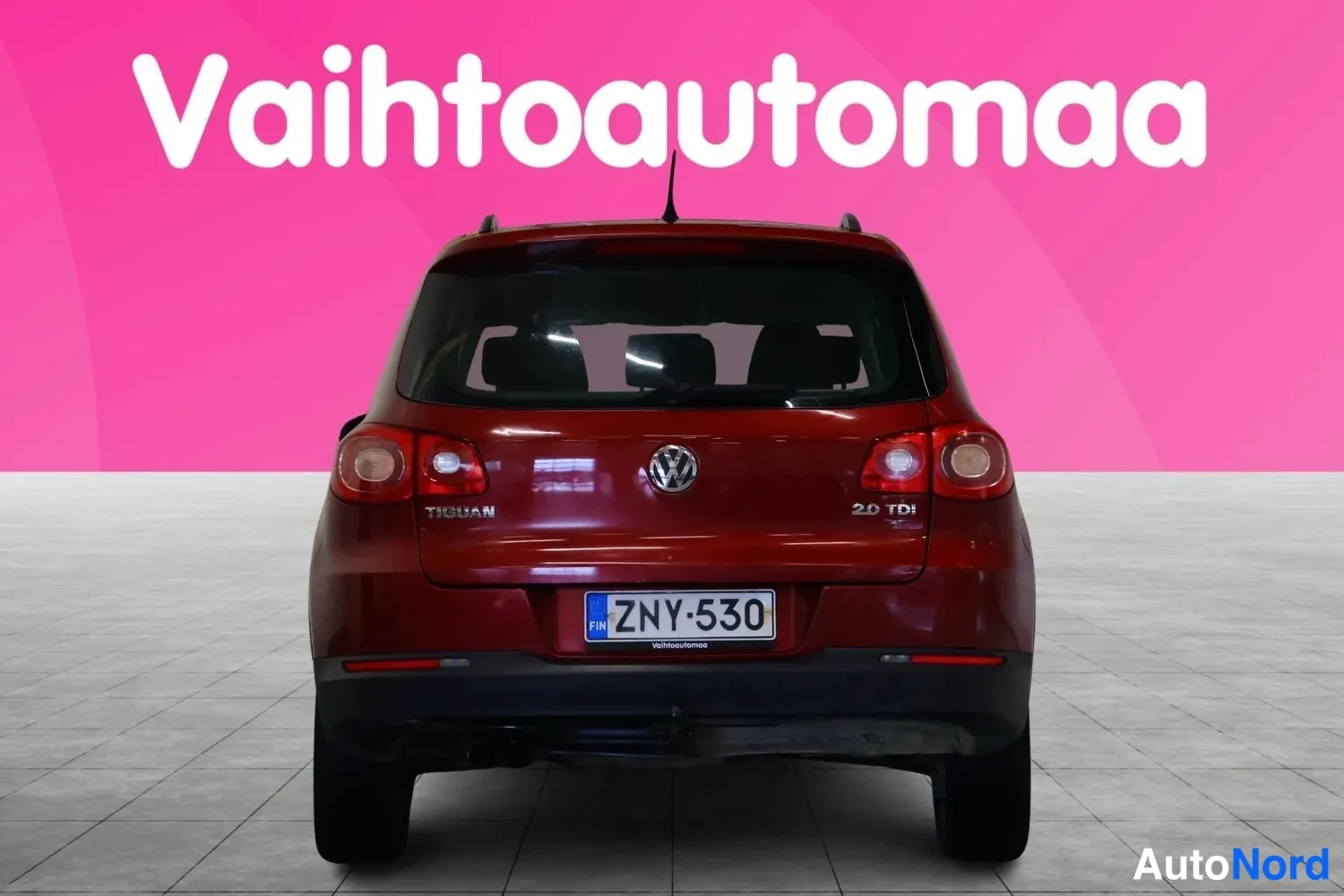Takaa: Punaisenruskean Volkswagen Tiguanin perä suoraan takaa, rekisteritunnus, peräovessa tekstit Tiguan ja 2.0 TDI.