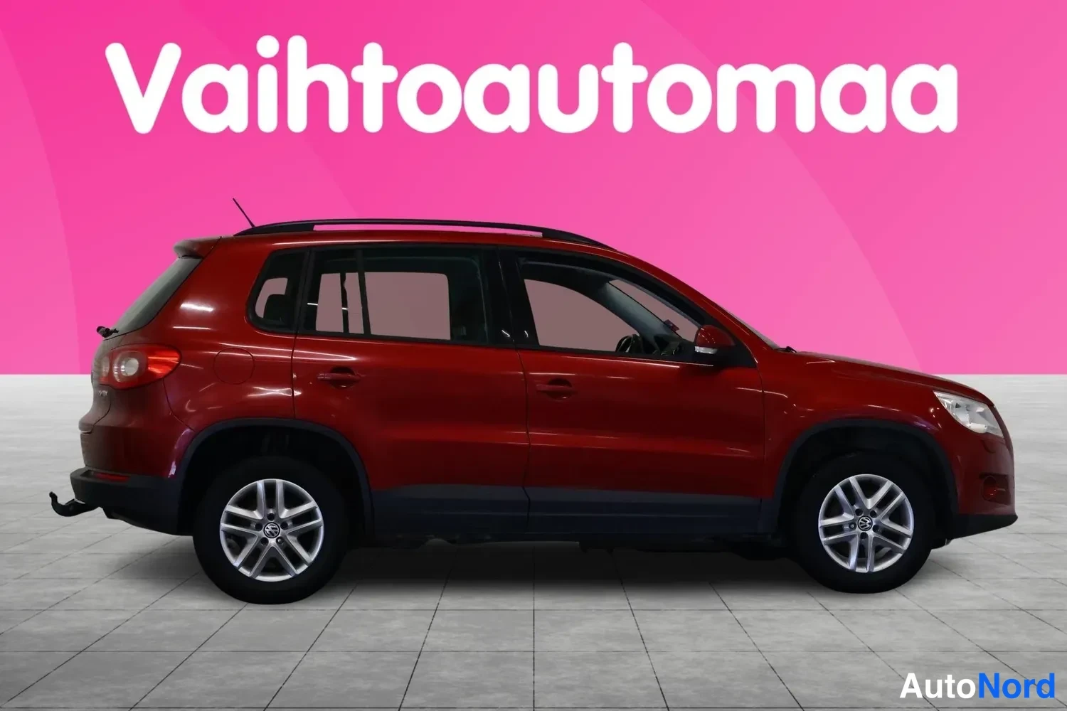 Etuviisto, nokka oikealle: Punaisen Volkswagen Tigualin kylki kolmivartinäkymässä keulan suuntaan, keula kuvan oikeassa reunassa.