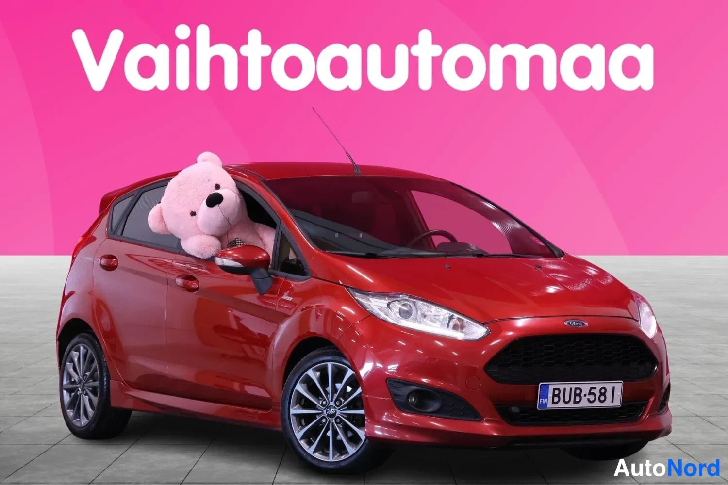 Etuviisto, nokka oikealle: Punainen Ford Fiesta etuviistöstä oikealta, rekisterikilpi.