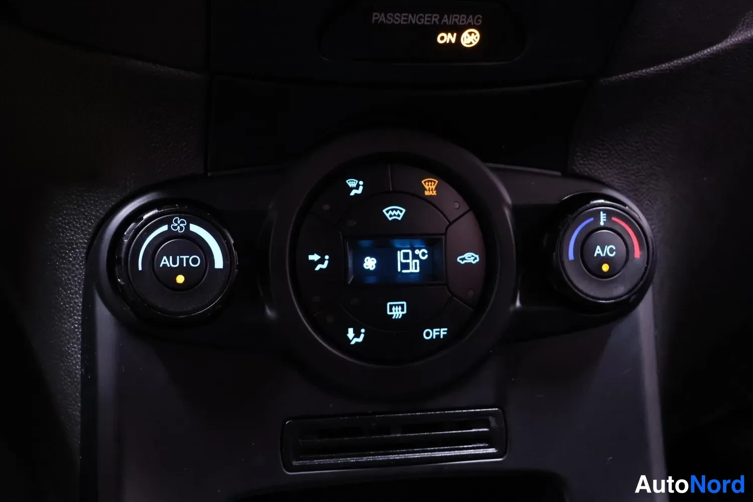 Muu: Automaattinen ilmastointipaneeli: AUTO-merkki, A/C-painike, näyttö 19°C, OFF, ja ylhäällä PASSANGER AIRBAG ON.