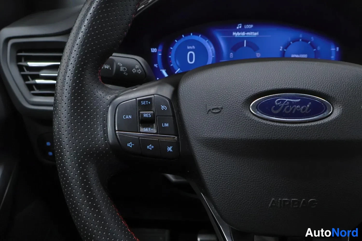 Edestä: Ohjauspyörän vasen puhallinclusteri: Ford-logon koristeama kuljettajan airbag-merkintä sekä cadence-, rajoitin- ja ääniohjainpainikkeet.