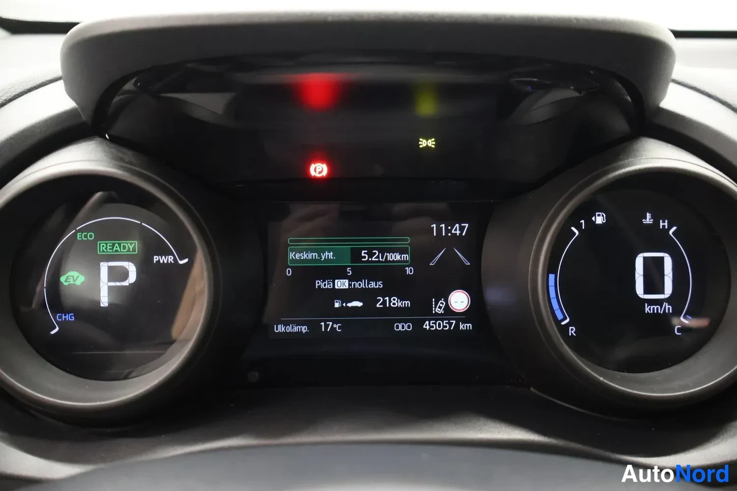 Yksityiskohta: Hybridiauton kojelauta: kierroslukumittarin sijaan CHG/PWR-mittari ja EV-merkki, keskinopeus 5,2 l/100km, matkamittari 45057 km, ulkolämpötila 17 °C, vaihde P j