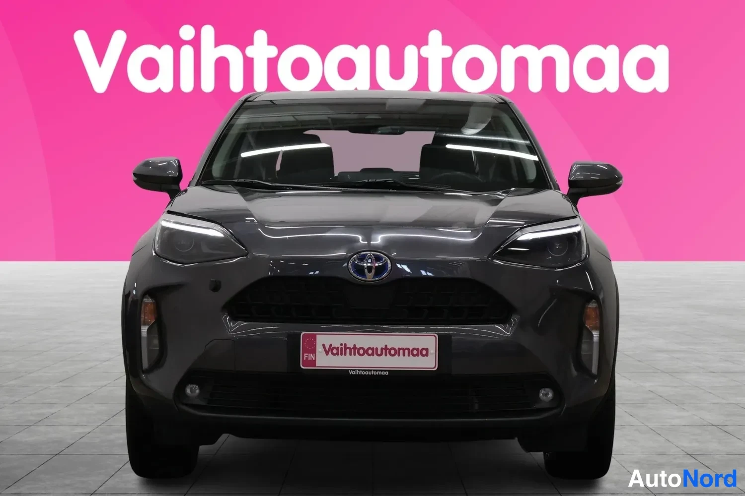 Edestä: Tummanharmaan Toyota Yaris Crossin etunäkymä suoraan edestä, Toyota-embleemi näkyvissä etusäleikössä.