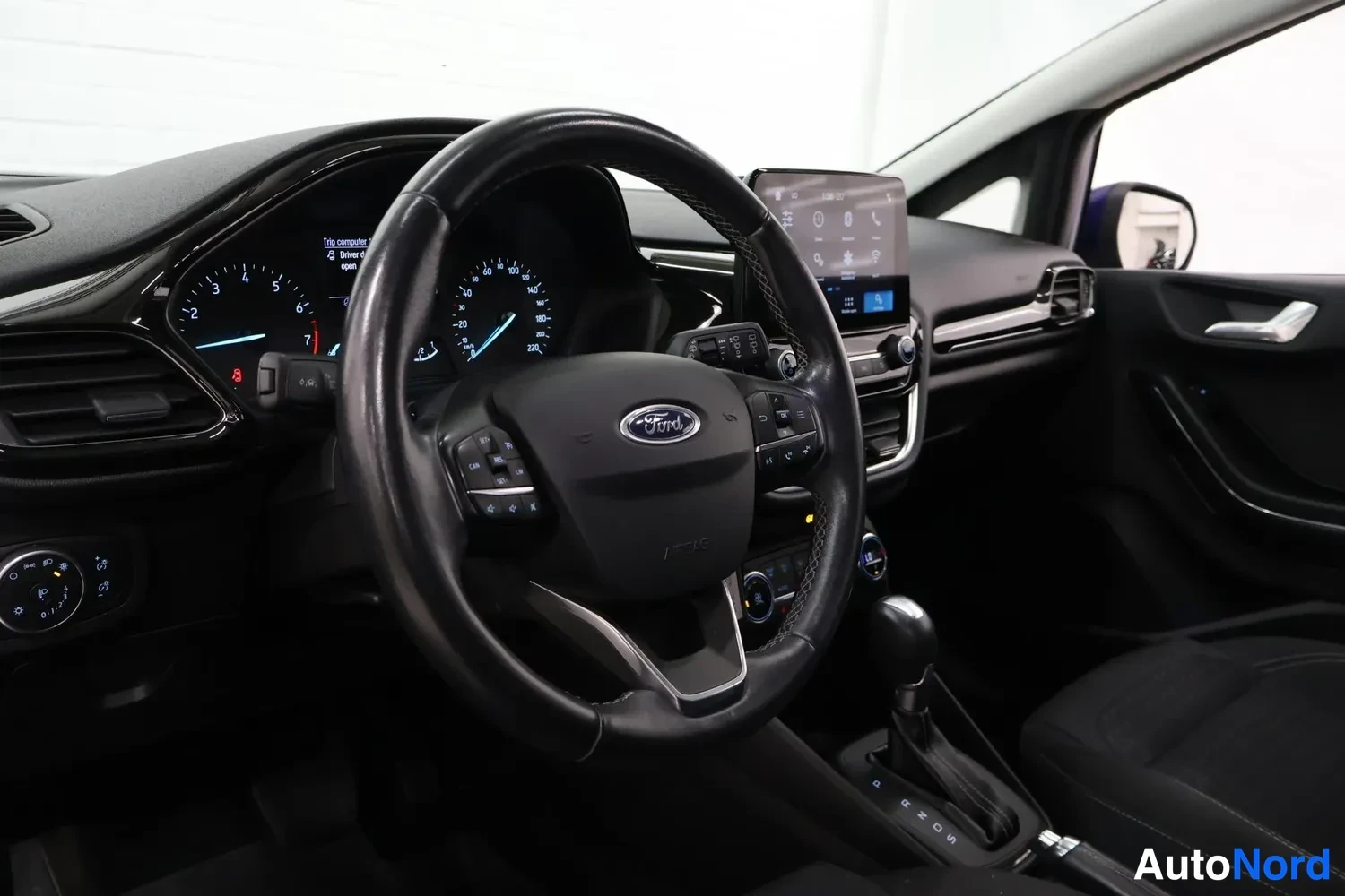 Muu: Ohjauspisteen näkymä: Ford-merkitty ohjauspyörä, mittaristo, kosketusnäyttö ja automaattivaihteen keila.
