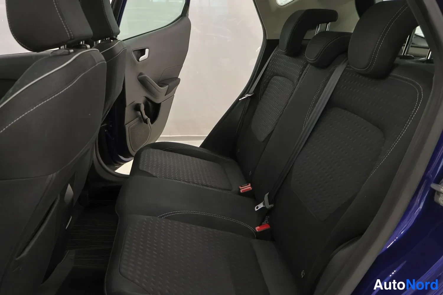 Muu: Ford Fiestan takaistuin ja avattu takaovi, mustat kangaspenkit ja sininen karmi.