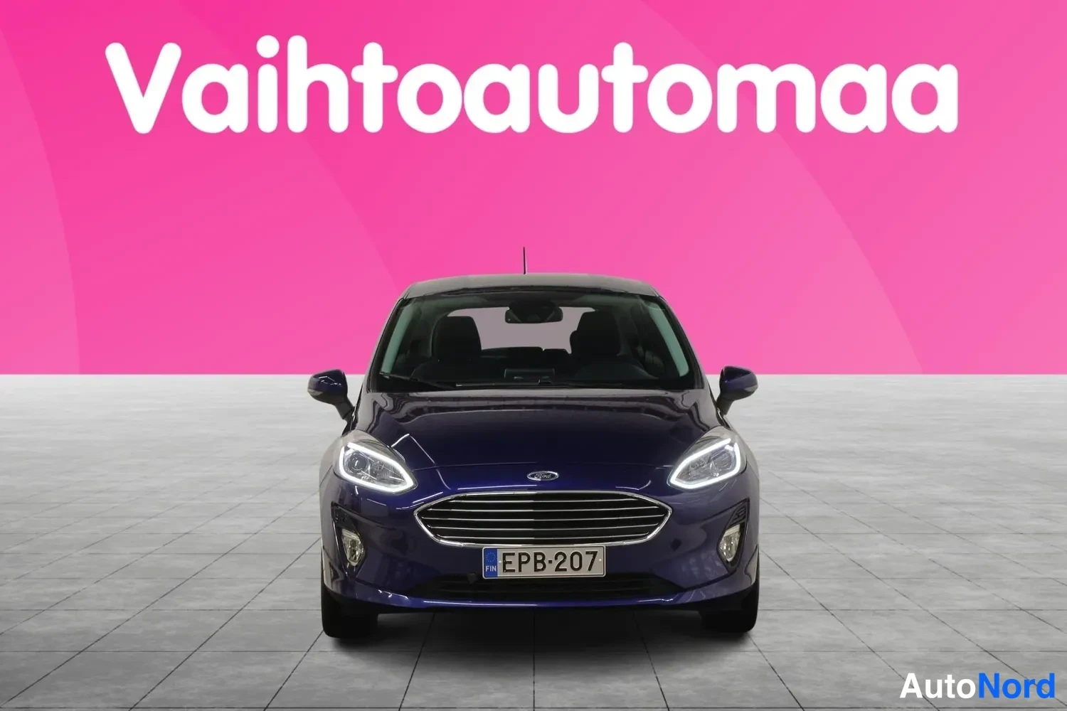 Edestä: Tummansininen henkilöauto suoraan edestä kuvattuna, rekisterikilpi.