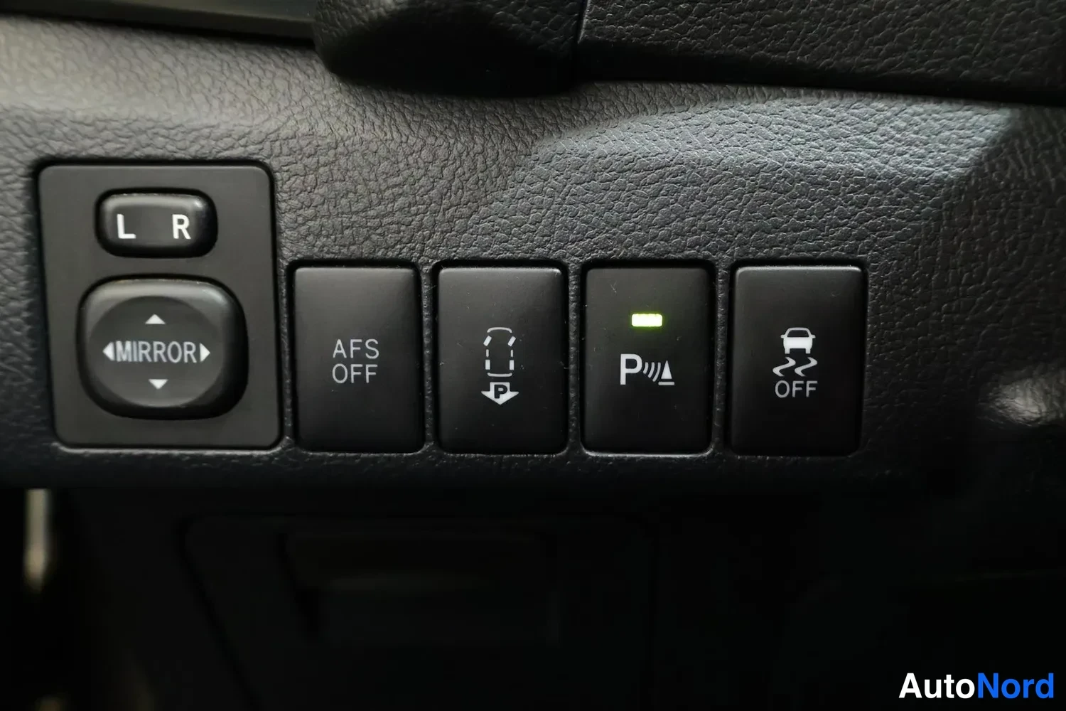 Yksityiskohta: Ohjaamon katupaneeli peilinsäädöllä (L/R ja MIRROR) sekä painikkeet AFS OFF, parking assist, parkointitutkan P-merkki (vihreä valo päällä) ja vakautus OFF.