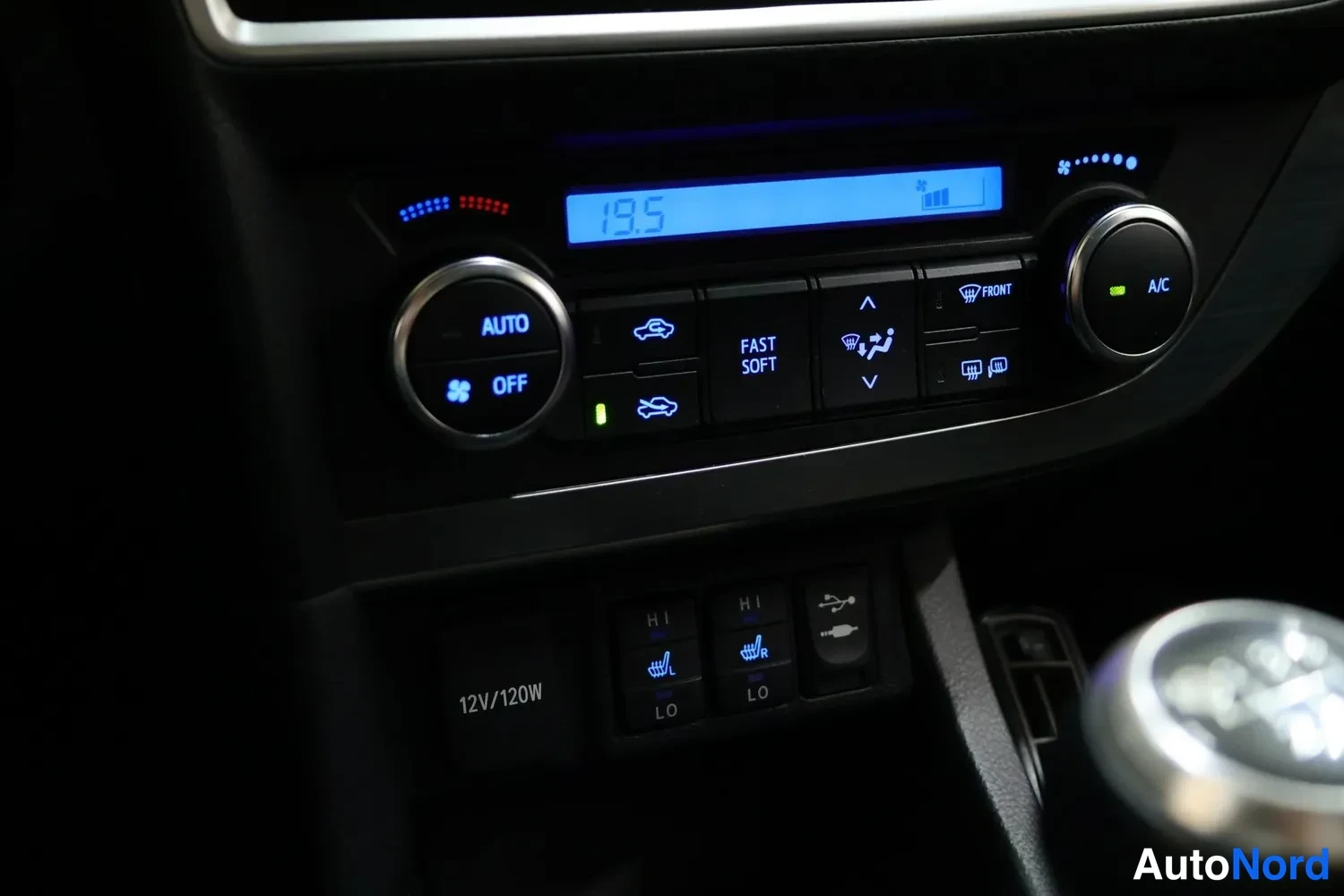 Yksityiskohta: Ilmastointipaneeli 19,5 asteen näytöllä, AUTO- ja A/C-napeilla, alla lämpöistuinten kytkimet (HI/LO) sekä 12V/120W-pistorasiakytkin.