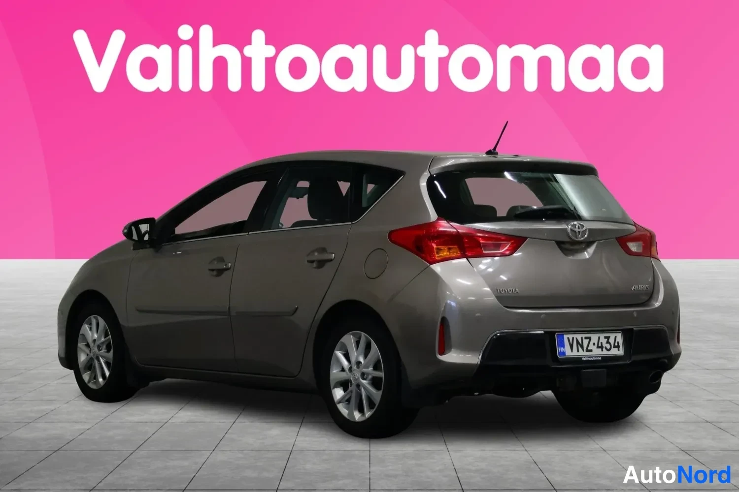 Takaviisto: Vaaleanharmaa Toyota Auris -henkilöauto takanurkkakulmasta, rekisteritunnus.