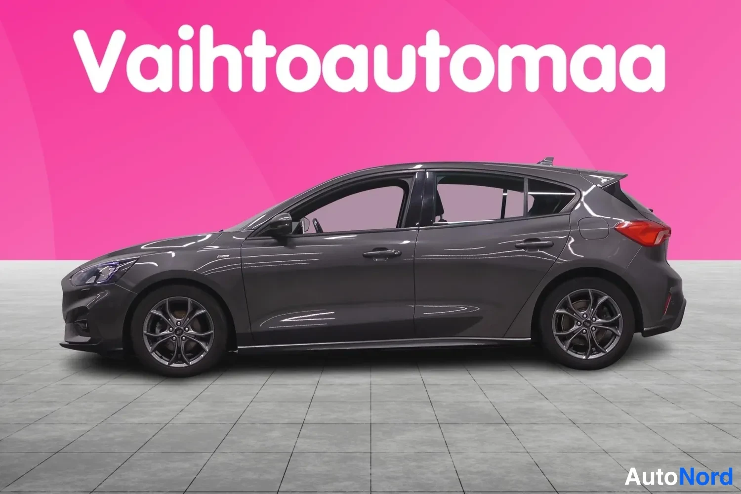 Sivulta: Tummanharmaan Ford Focus -henkilöauton sivuprofiili sisätiloissa.