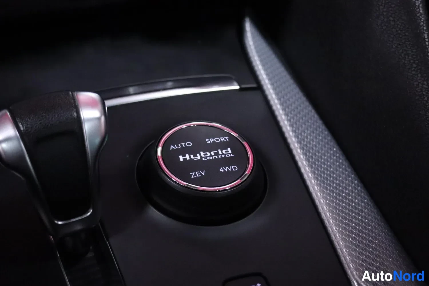 Muu: Vaihtimen vieressä oleva pyöreä ajotilan valitsin, jossa tekstit AUTO, SPORT, ZEV ja 4WD sekä Hybrid control -merkintä.