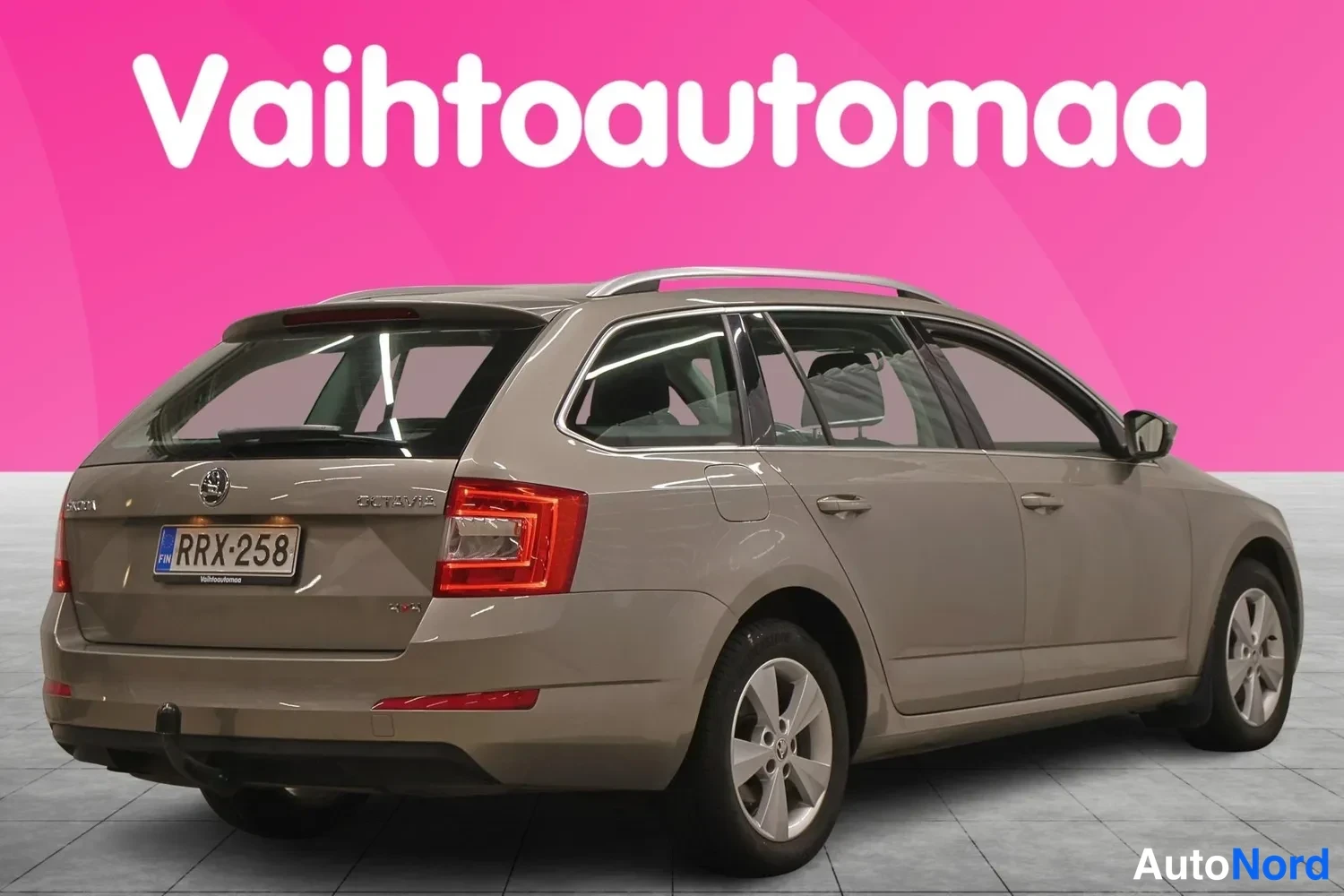 Takaviisto: Skoda Octavia -farmarin takaosa ja vasen sivu kolmeneljäsosakuvaan kuvattuna, kori on beige, rekisterikilpi ja takaluukussa Skoda-merkintä.