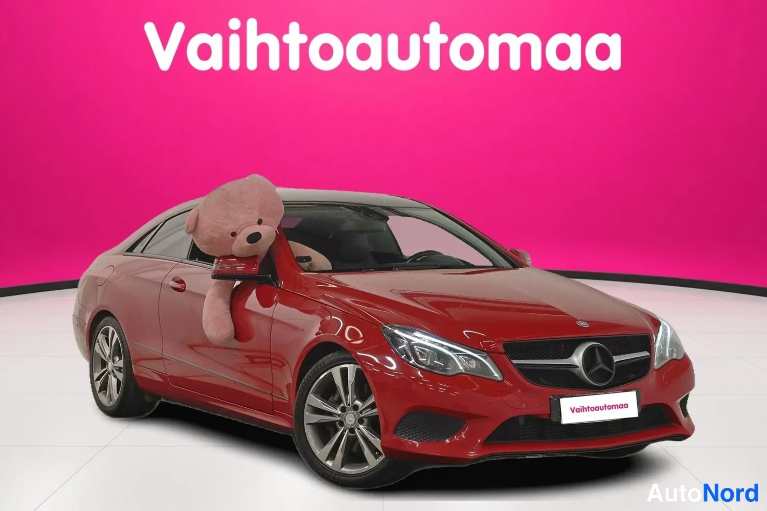 Etuviisto, nokka oikealle: Punainen Mercedes-Benz E 200 -coupe etu Kolmasosakulmassa, keula oikealla, suuressa peilipallossa vaaleanpunainen pehmoleluikkunasta.