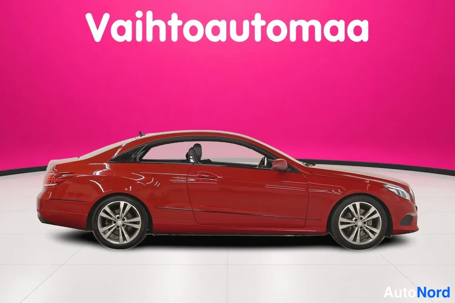 Etuviisto, nokka oikealle: Punainen Mercedes-Benz-kupea sivulta etunojan suuntaan studioassa; kylki, ajovalo ja metallivanteet näkyvät selkeästi.
