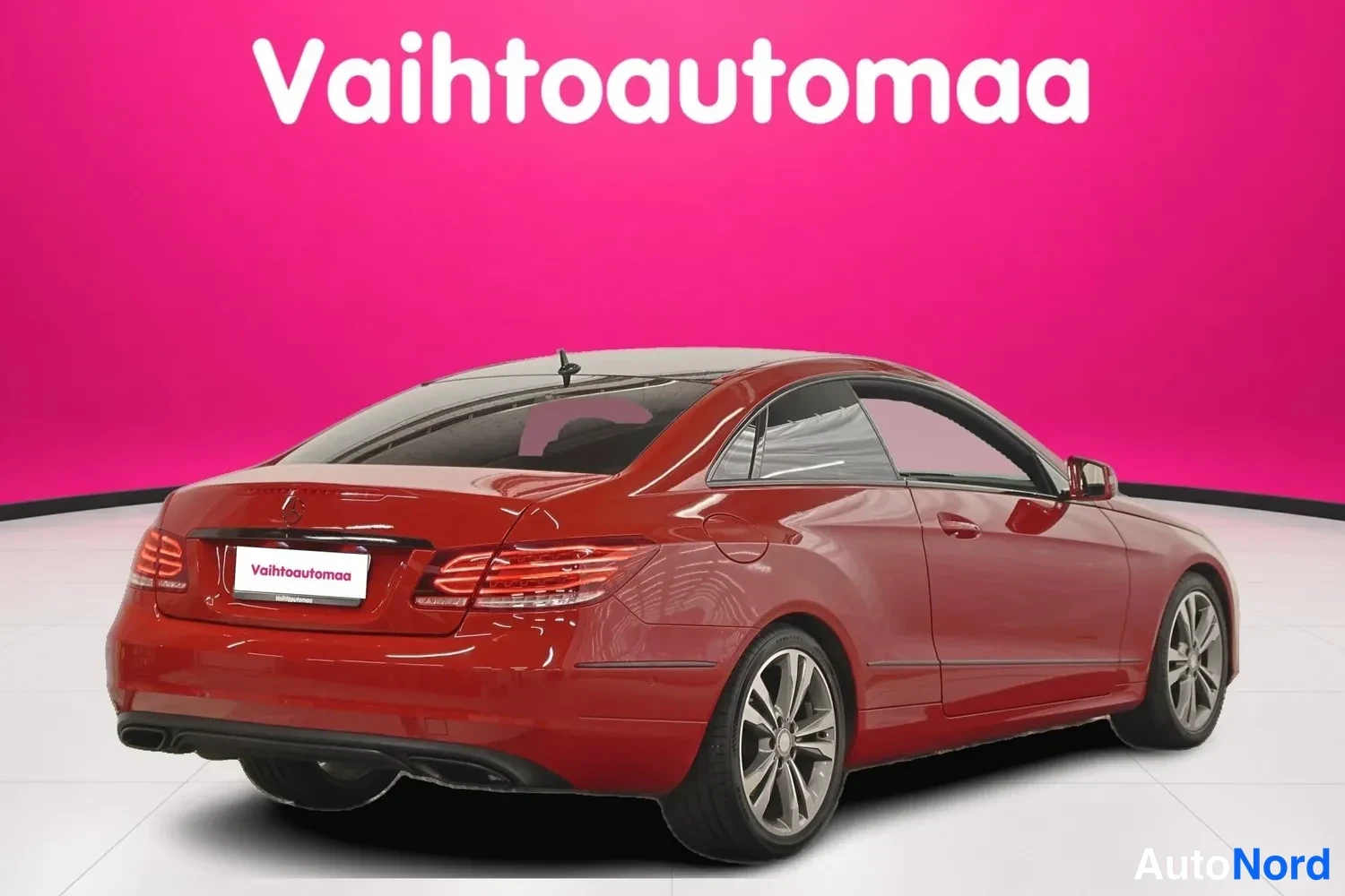 Takaviisto: Punaisen Mercedes-Benzin takanurkkakuva studioassa; perävalot, konepelti ja metallivanteet näkyvät vaaleaa lattiaa vasten.
