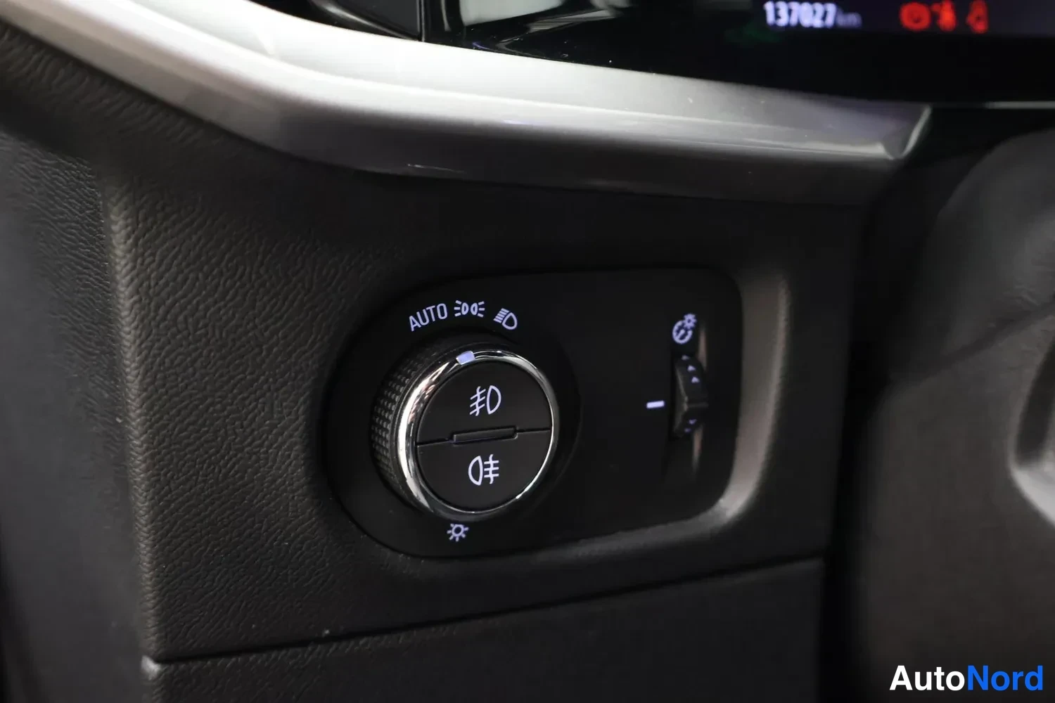 Yksityiskohta: Sisätilakuva: auton valokytkin, jossa AUTO-merkintä ja sumuvalosymbolit.