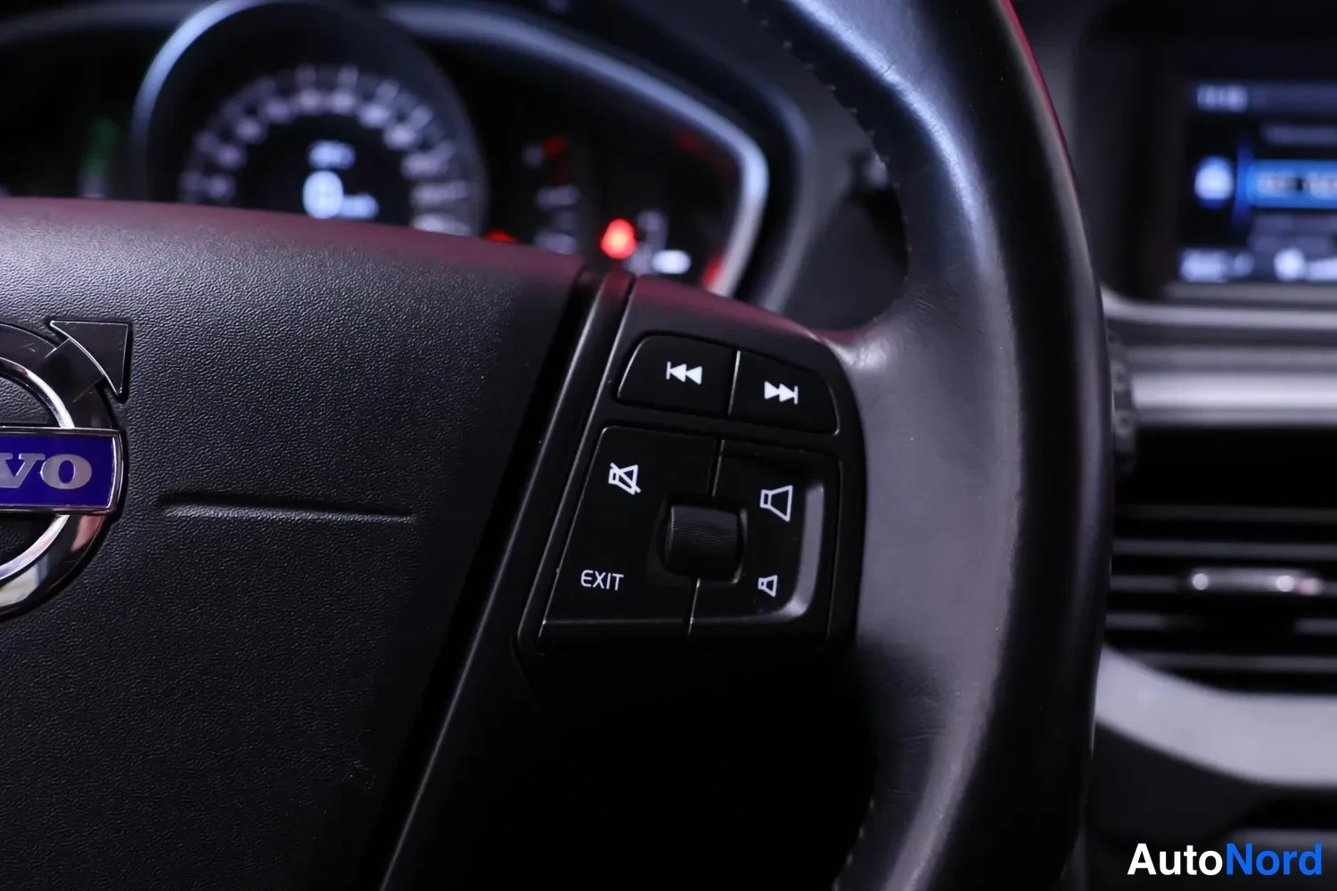 Muu: Volvo-ohjauspyörä lähikuvassa, hallintanapeilla ja mittaristo taustalla.