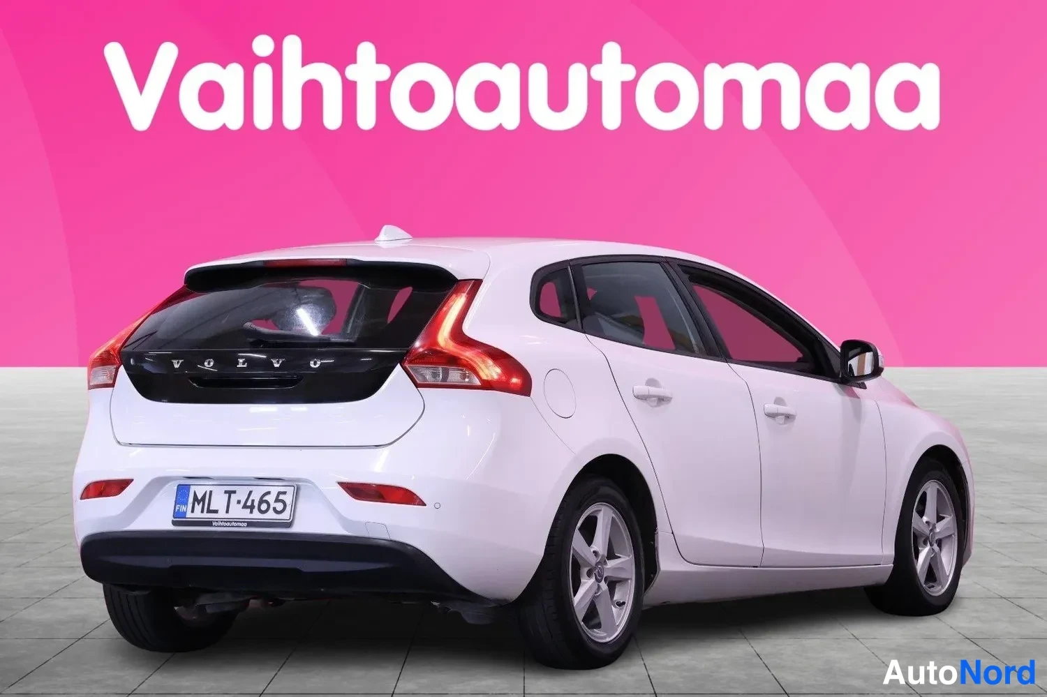 Takaviisto: Valkoinen Volvo V40 takaokolikuvassa, rekisteritunnus, pinkki tausta.