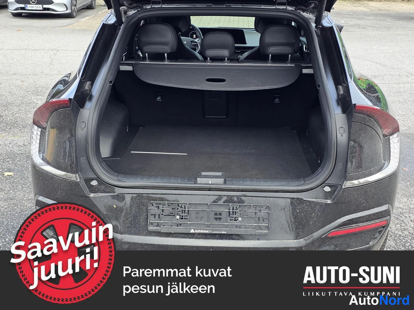 Takaa: Auki avattu tavaratila takaapäin: tummat verhoilut, taittetut takaselkänojat ja takavalojen palat erottuvat.