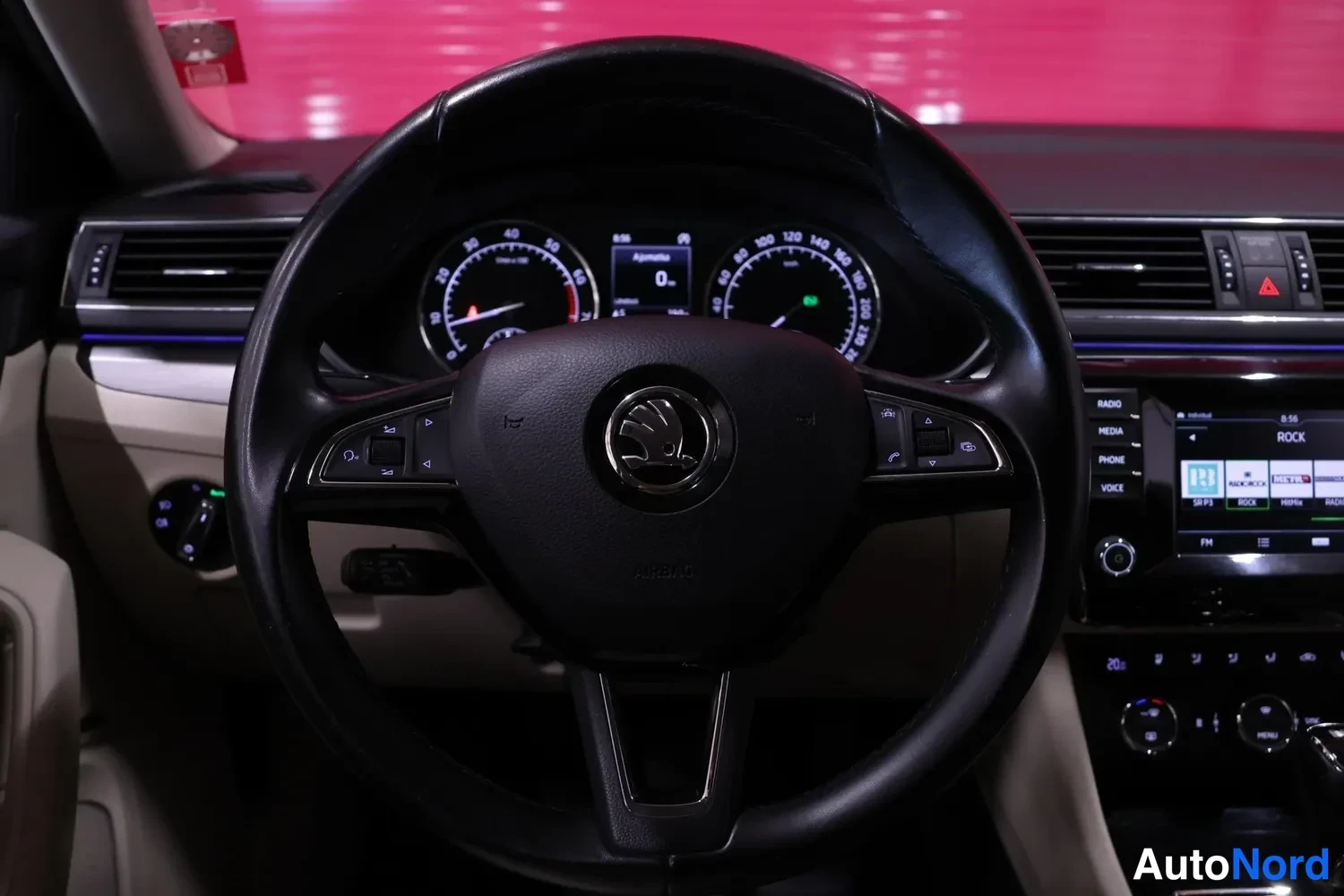 Muu: Ohjauspyörä ja kojelauta sisätiloissa: Skoda-merkki pyörän nupissa, mittarit ja kosketusnäyttö näkyvät taustalla.