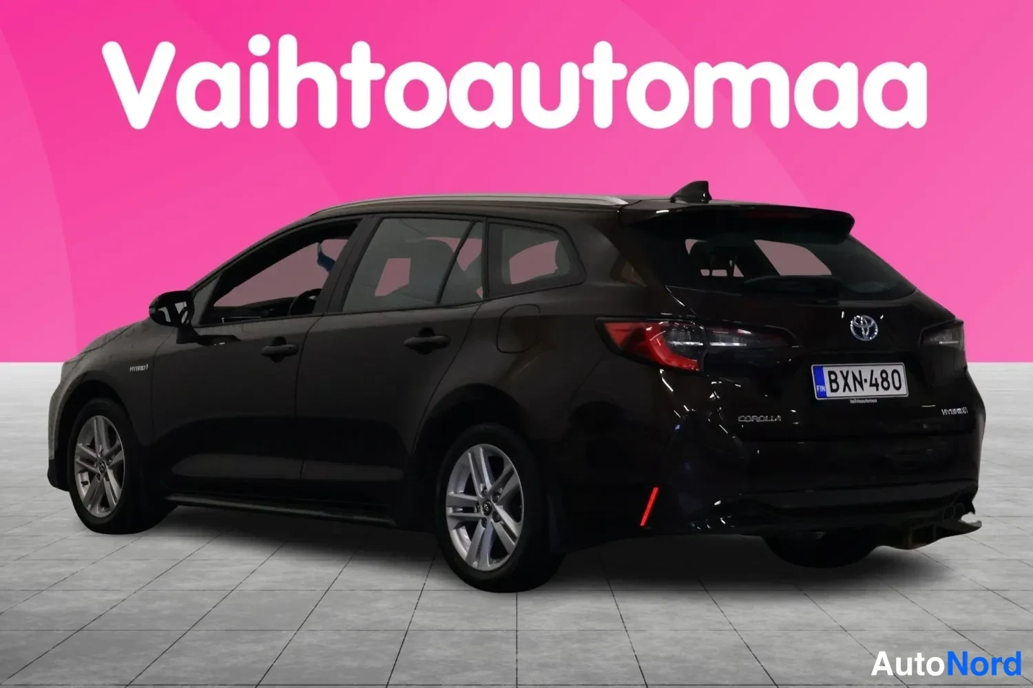 Takaviisto: Mustanruskea Toyota Corolla Touring Sports -farmari vinosti takaa oikealta, rekisterikilpi.