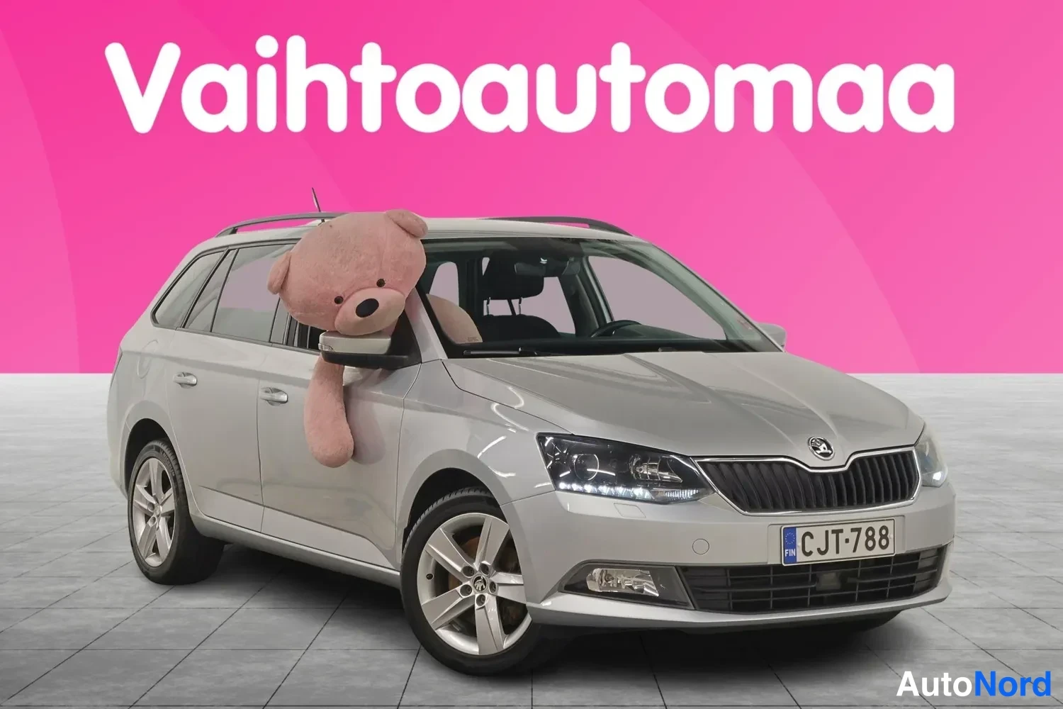 Etuviisto, nokka oikealle: Hopeanharmaa farmariauto kolmesivukulmassa, keulakuva oikealle suunnattuna; rekisterikilpi, kattoon asennetut kaiteet ja pehmoikkunassa.