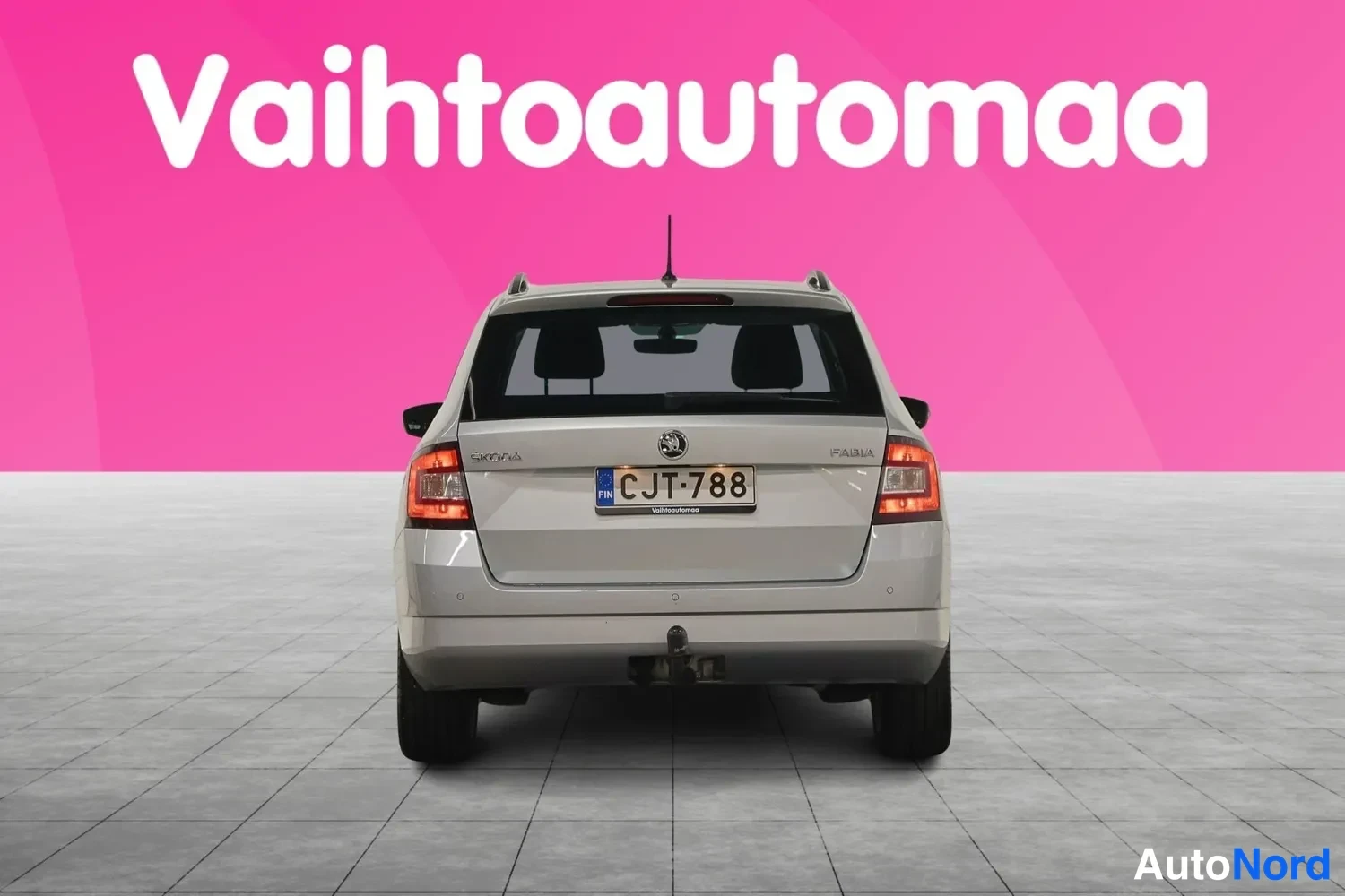 Takaa: Hopeanharmaa farmariauto suoraan takaa kuvattuna, rekisteritunnus, takavetokoukku näkyvissä.